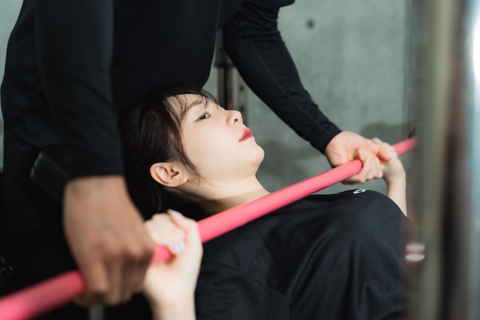 トレーナーが補助しながら行うプレス種目のフォーム指導
